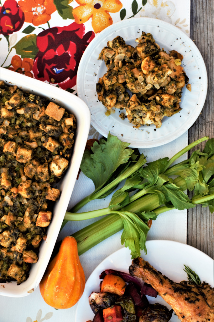a display of oyster stuffing in a casserole dish next to a plate and celery and carrots on the counter