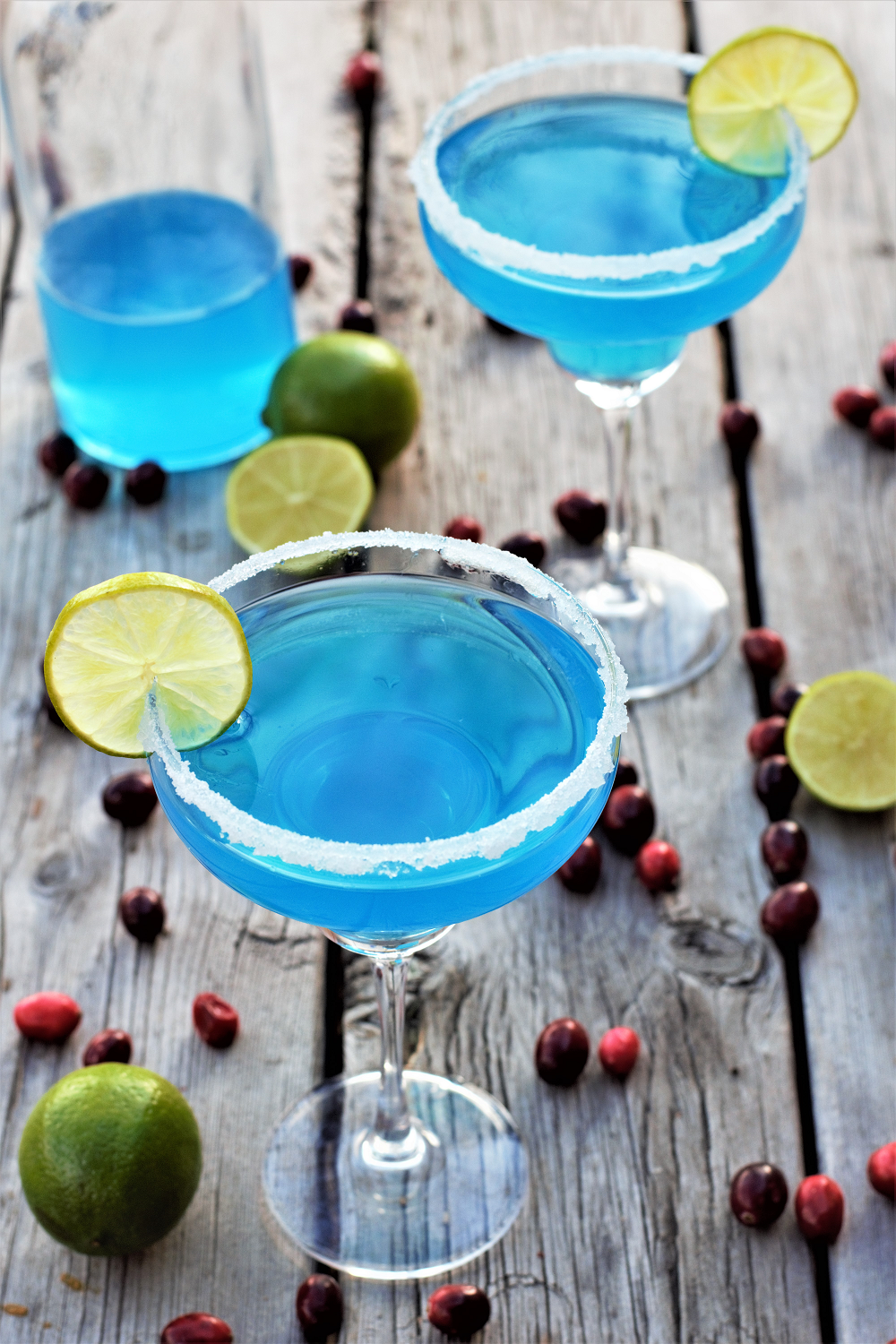 Gorgeous icy blue cocktails with rum, white cranberry, curacao, & lime rimmed with sparkling snowflake sugar to bring on the snow for a blue blue Christmas!