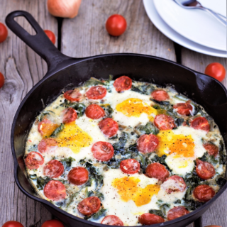 Easy one-dish kale-stuffed skillet starts on the stovetop with a big handful of cherry tomatoes, then slides into the oven to bake egg yolks to gooey, salty perfection.